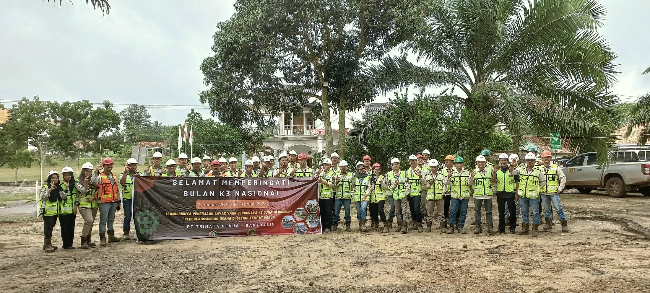 Full site crew in high-visibility vests and hard hats lined up behind a National K3 safety month banner.